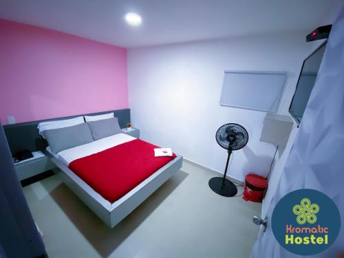 a bedroom with a red and white bed and a fan at Kromatic Hostel in Medellín