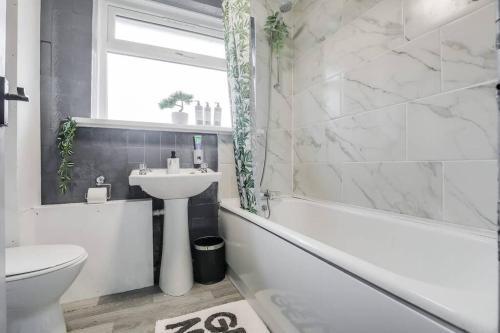 a bathroom with a sink and a toilet and a tub at Stylish 3 Bed House Close to NEC in Birmingham
