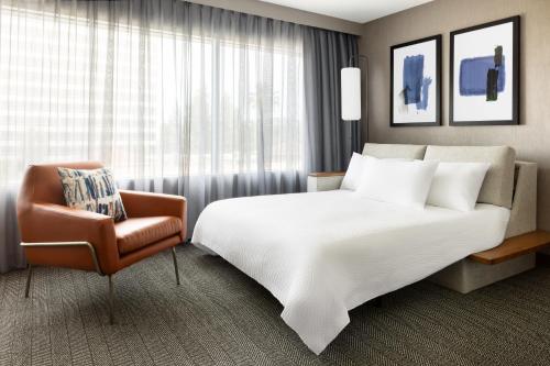 a hotel room with a large bed and a chair at Courtyard by Marriott Los Angeles Woodland Hills in Woodland Hills