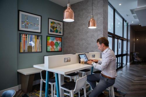 a man sitting at a table with a laptop at Holiday Inn Newcastle Gosforth Park by IHG in Newcastle upon Tyne