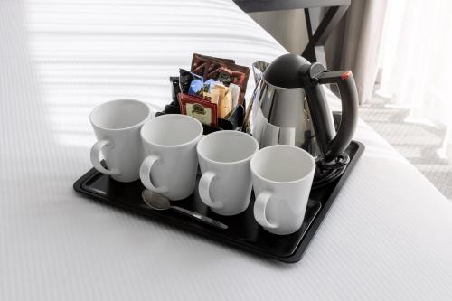 a tray with cups and a coffee maker on a bed at Holiday Inn Newcastle Gosforth Park by IHG in Newcastle upon Tyne