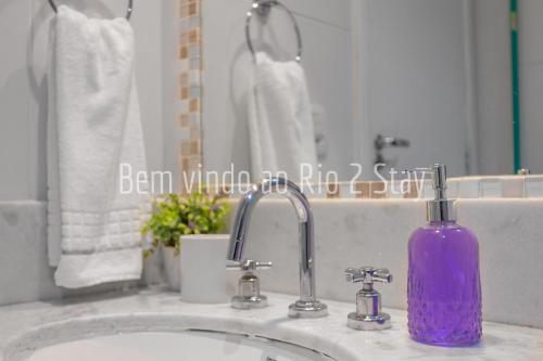 uma garrafa de sabão roxa sentada num lavatório da casa de banho em 10 Suite Verano Stay Barra no Rio de Janeiro