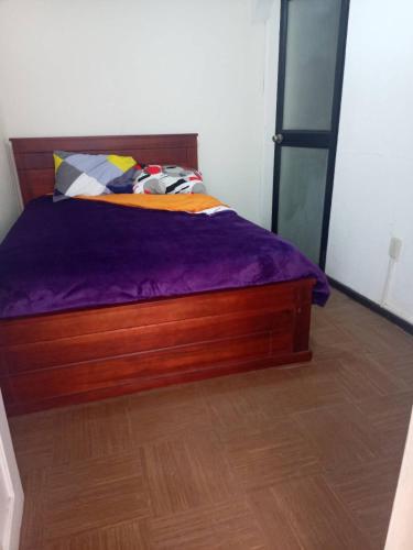 um quarto com uma cama de madeira e lençóis roxos em 悦来客栈 em Quito