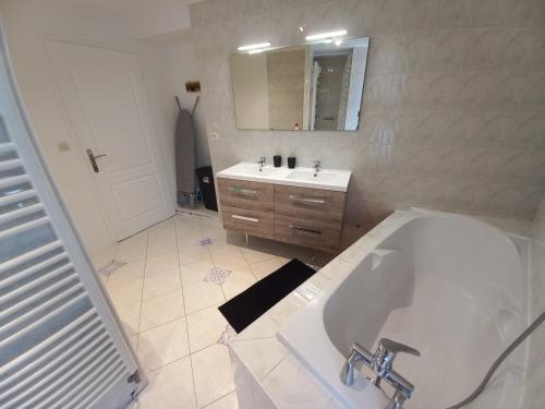 La salle de bains blanche est pourvue d'une baignoire et d'un lavabo. dans l'établissement Maison à 5 minutes du lac à pied, à Aix-les-Bains