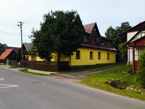una casa amarilla al lado de una calle en Pod limbą, en Jurgów