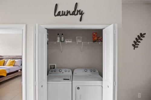 a laundry room with two washing machines and a bed at Luxury and tranquility, In the Heart of Poinciana, just 30 min from Disney! in Poinciana