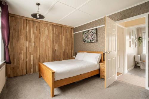 1 dormitorio con 1 cama y pared de madera en Quiet 2 bedroom home with cozy fire., en Ebchester