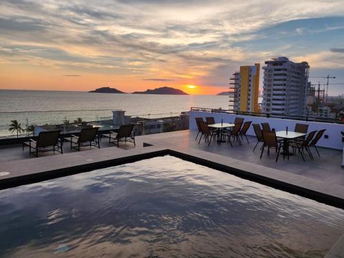 a swimming pool on the roof of a building with a sunset at Torre Q Mazatlán - Departamento cerca del malecón de Mazatlán in Mazatlán