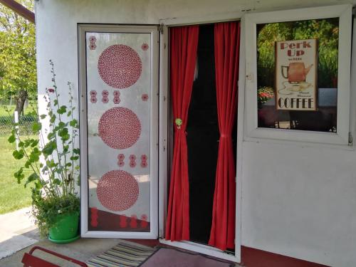 a door of a house with a red curtain at Blossom Cottage - Sustainable Tourism Retreat in Laktaši