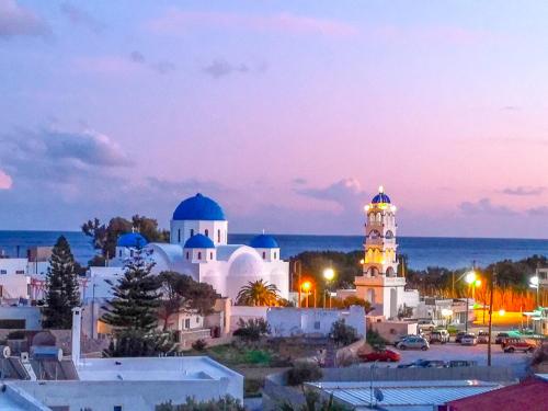 una vista de la ciudad por la noche con una mezquita en Villa Dima, en Perissa