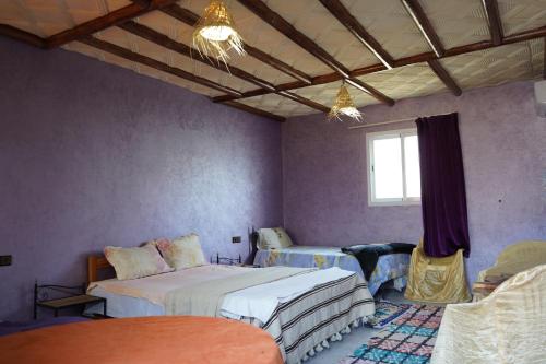 a bedroom with two beds and a window at Chez Imnir in Ijjoukak