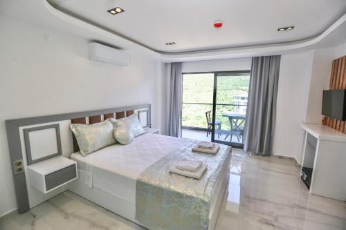 a white bedroom with a bed and a balcony at Stonehillkaş in Kas