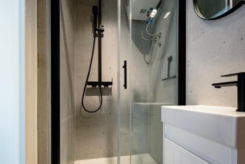 um chuveiro com uma porta de vidro ao lado de um lavatório em CITY BREAK Studio apartments em Šibenik