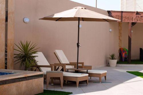 a patio with two chairs and an umbrella at Alhussam Villa & Chalet - Dead Sea in Al Rama
