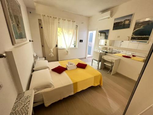 Un dormitorio con una cama amarilla y blanca y una cocina. en Enjoy Tropea Accomodation, en Tropea