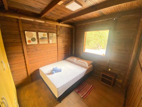een klein bed in een houten kamer met een raam bij Recanto da Felicidade para 13 pessoas in Annitapolis