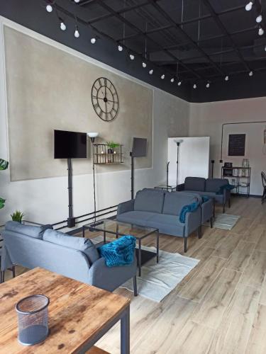 a living room with couches and a clock on the wall at Albergue HR in Sarria