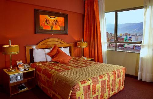 コチャバンバにあるCesar's Plaza Hotelのベッドと大きな窓が備わるホテルルームです。