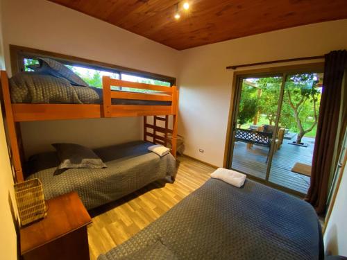 a bedroom with two bunk beds and a balcony at Cabañas La Luz in Olmué