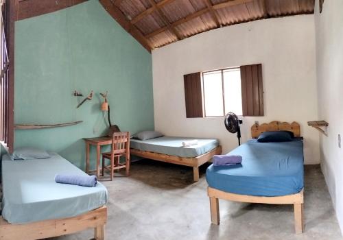 a room with two beds and a table and a desk at Cabañas La Escondida Mazunte in Mazunte