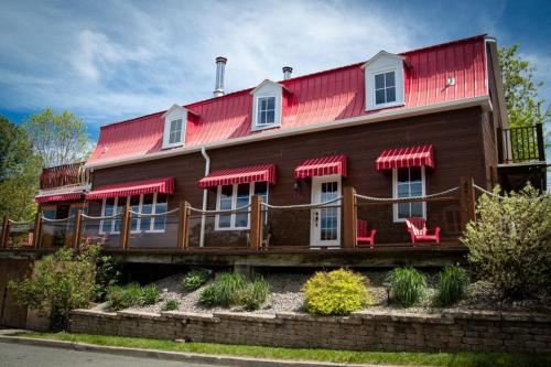 a wooden house with a red roof at Chalet & Gîte Capitainerie du Passant in Grandes-Piles