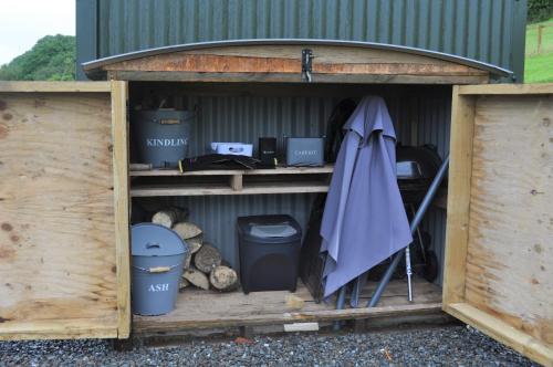 a shed with trash cans and an umbrella in it at Fullabrook Farm Retreat, The Shepherdess Hut in West Down