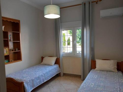 1 dormitorio con 2 camas y ventana en Aggeliki's place detached home with yard/parking, en Volos