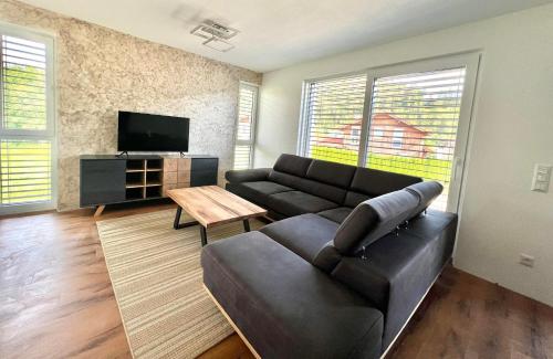 a living room with a black couch and a tv at Alpin Apartments in Radstadt