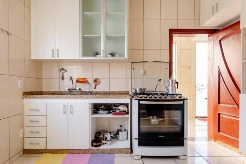 una cocina con armarios blancos y horno negro en Trem bão de dormir hostel en Belo Horizonte
