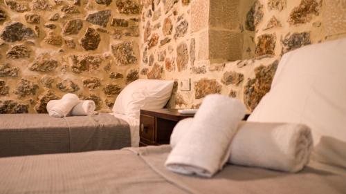 a bedroom with two beds and a stone wall at Mitato Eagle's Nest Peristeres in Níthavris