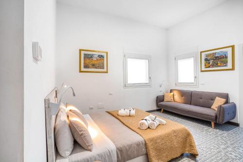een witte slaapkamer met een bed en een bank bij Suite Mariagiovanni in Lecce