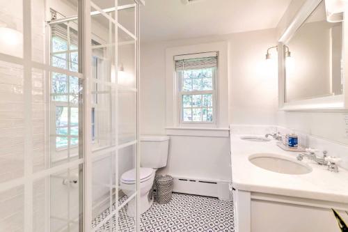 a white bathroom with a toilet and a sink at Walkable Dennis Cottage The Blue Scallop in Dennis