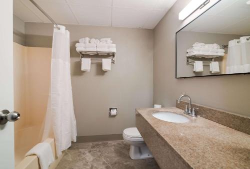 a bathroom with a sink and a toilet and a mirror at Quality Inn & Suites in South Portland