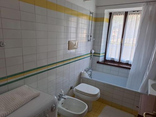 een badkamer met een toilet, een bad en een wastafel bij Il tuo nido sulle Dolomiti, con vista panoramica! in Calalzo