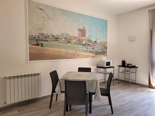 ein Esszimmer mit einem Tisch und einem Gemälde an der Wand in der Unterkunft Rooms da Pisicchio in Fiumicino