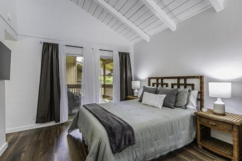 a white bedroom with a bed and a window at Sandpiper 216B condo in Princeville