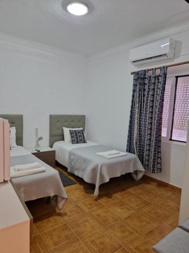 a bedroom with two beds and a window at Residencial Antonio Mocisso Guesthouse in Elvas