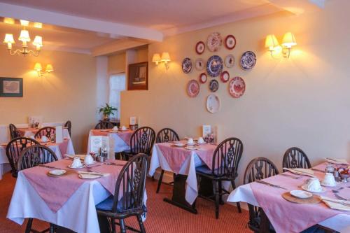 a dining room with tables and chairs and plates on the wall at Kersbrook Guest Accommodation in Lyme Regis