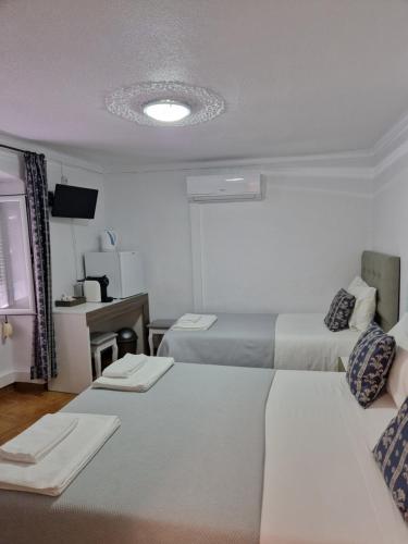 a hotel room with two beds and a desk at Residencial Antonio Mocisso Guesthouse in Elvas