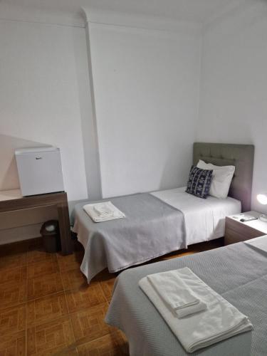 a small room with two beds and a table at Residencial Antonio Mocisso Guesthouse in Elvas