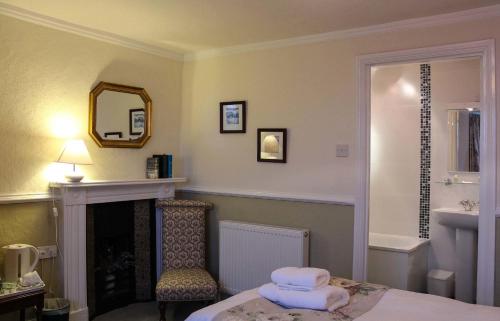 a room with a fireplace and a chair and a mirror at Kersbrook Guest Accommodation in Lyme Regis