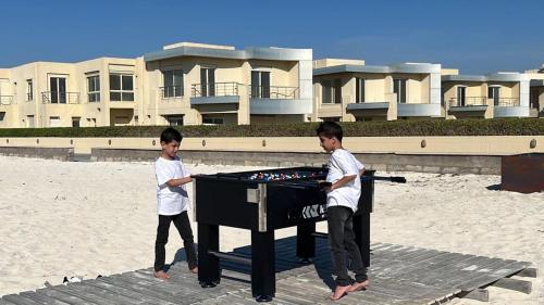two young boys playing a table on the beach at North coast Sedra Resort Chalet قريه سيدرا الساحل الشمالي علي البحر شاليه ثلاث غرف in Alexandria