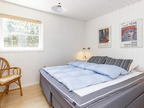 1 cama en un dormitorio con silla y ventana en Holiday Home Kallesensvej, en Blåvand