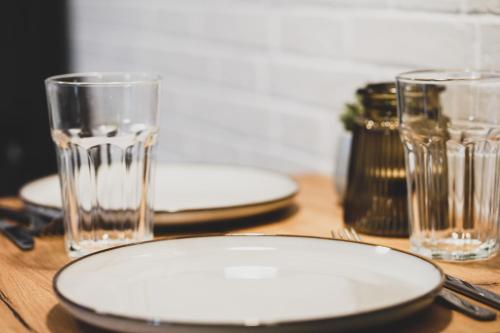 einem Holztisch mit zwei Tellern und Gläsern darauf in der Unterkunft Modernes Wohlfühl-Apartment an den Kaiserthermen in Trier