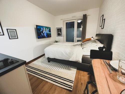 ein weißes Schlafzimmer mit einem Bett und einem Tisch in der Unterkunft Modernes Wohlfühl-Apartment an den Kaiserthermen in Trier