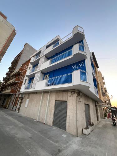 a large building with blue windows on a street at M&M rooms Margherita di Savoia in Margherita di Savoia