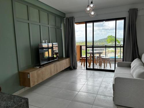 a living room with a couch and a view of a patio at Flat Eco Resort Carneiros in Praia dos Carneiros