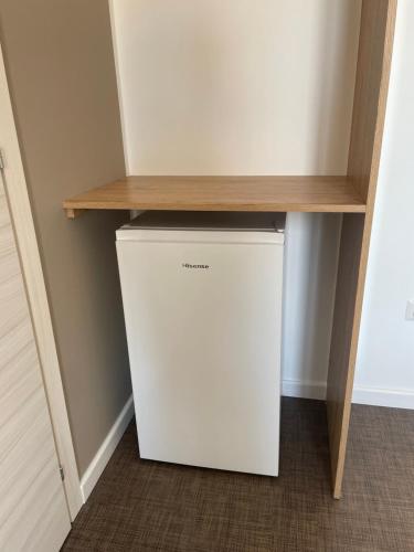a small white refrigerator in a room with a wooden shelf at M&M rooms Margherita di Savoia in Margherita di Savoia