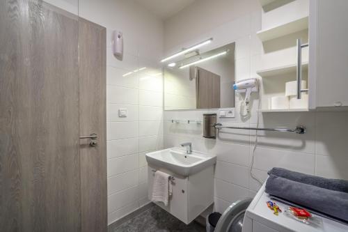 W białej łazience znajduje się umywalka i lustro. w obiekcie Rezidencia pri Radnici w Koszycach