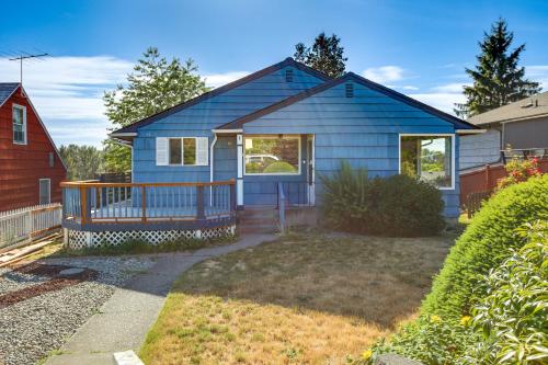 a blue house with a porch and a yard at Updated Tacoma Home with Fire Pit! in Tacoma